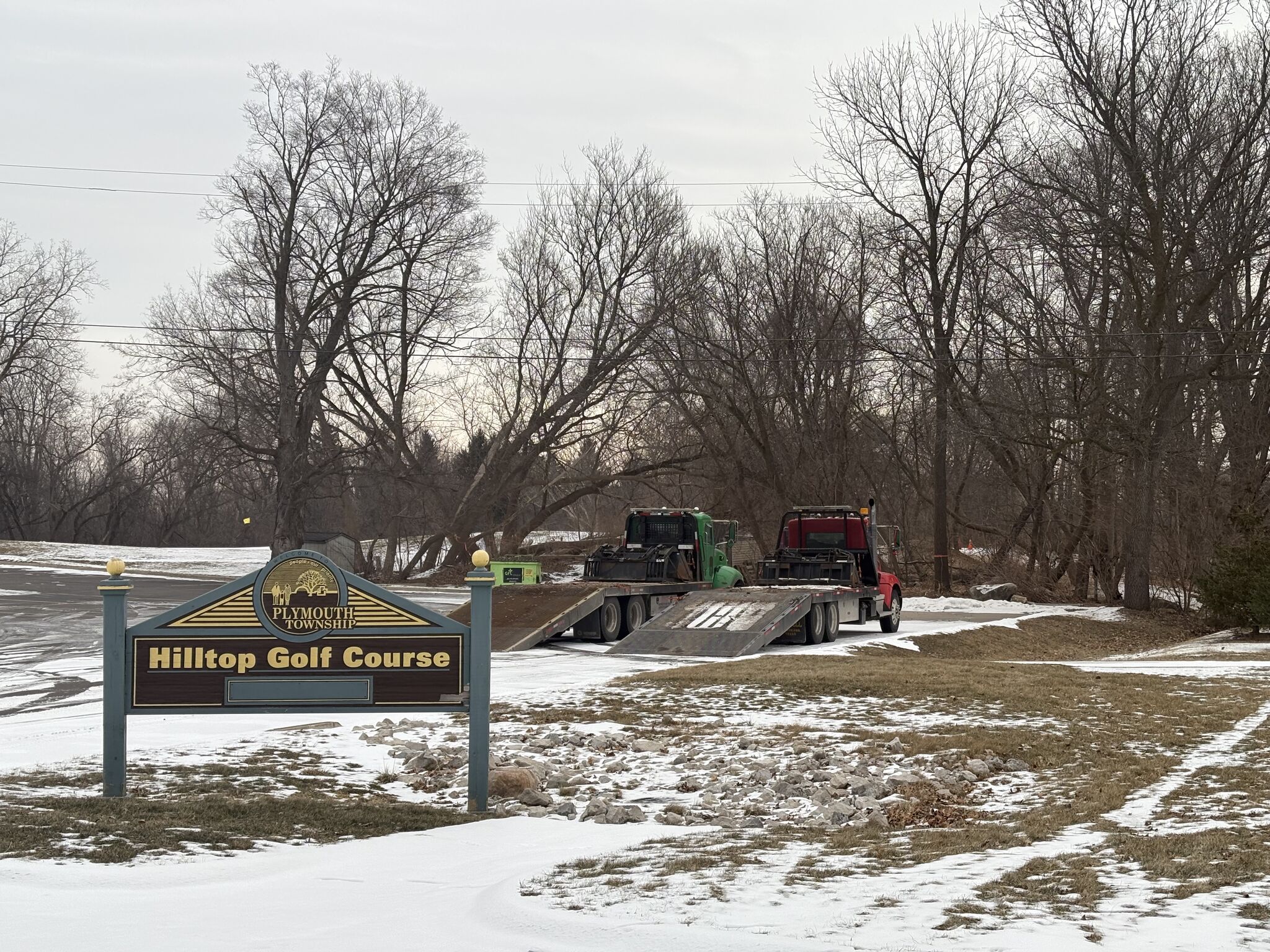 Equipment and trucks at Hilltop Golf Course in Plymouth Township, preparing for land clearing services in winter.